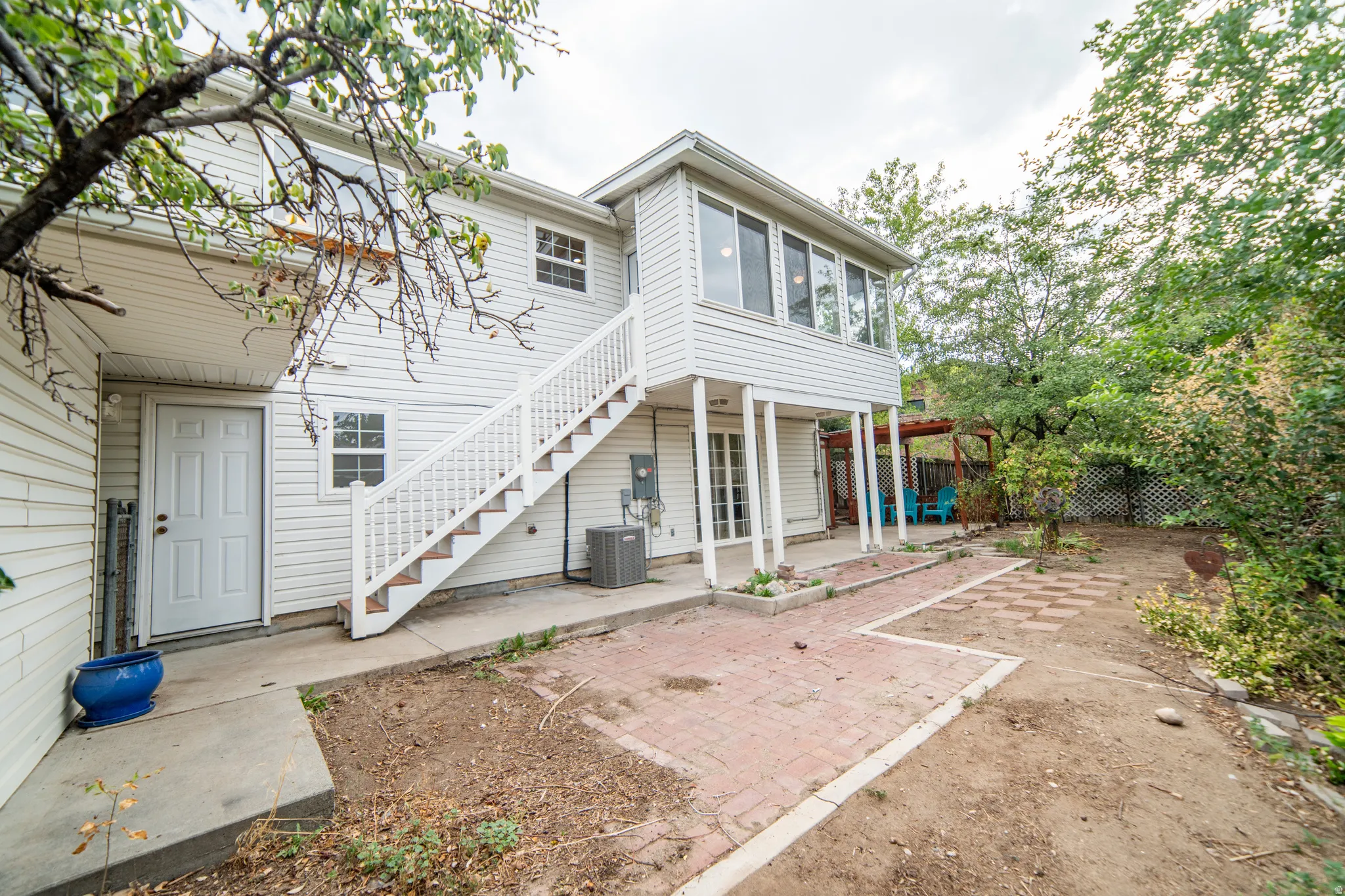 Exterior with white siding, ground-level entry door, and an elevated sunroom with extensive windows