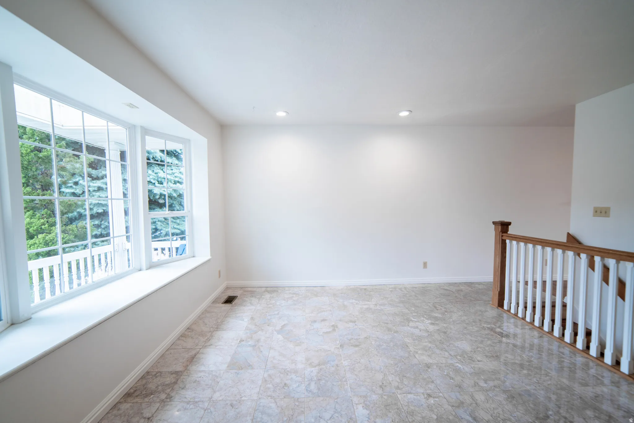 Bay window with white trim, recessed lighting, tile flooring, and wood and white-painted railing