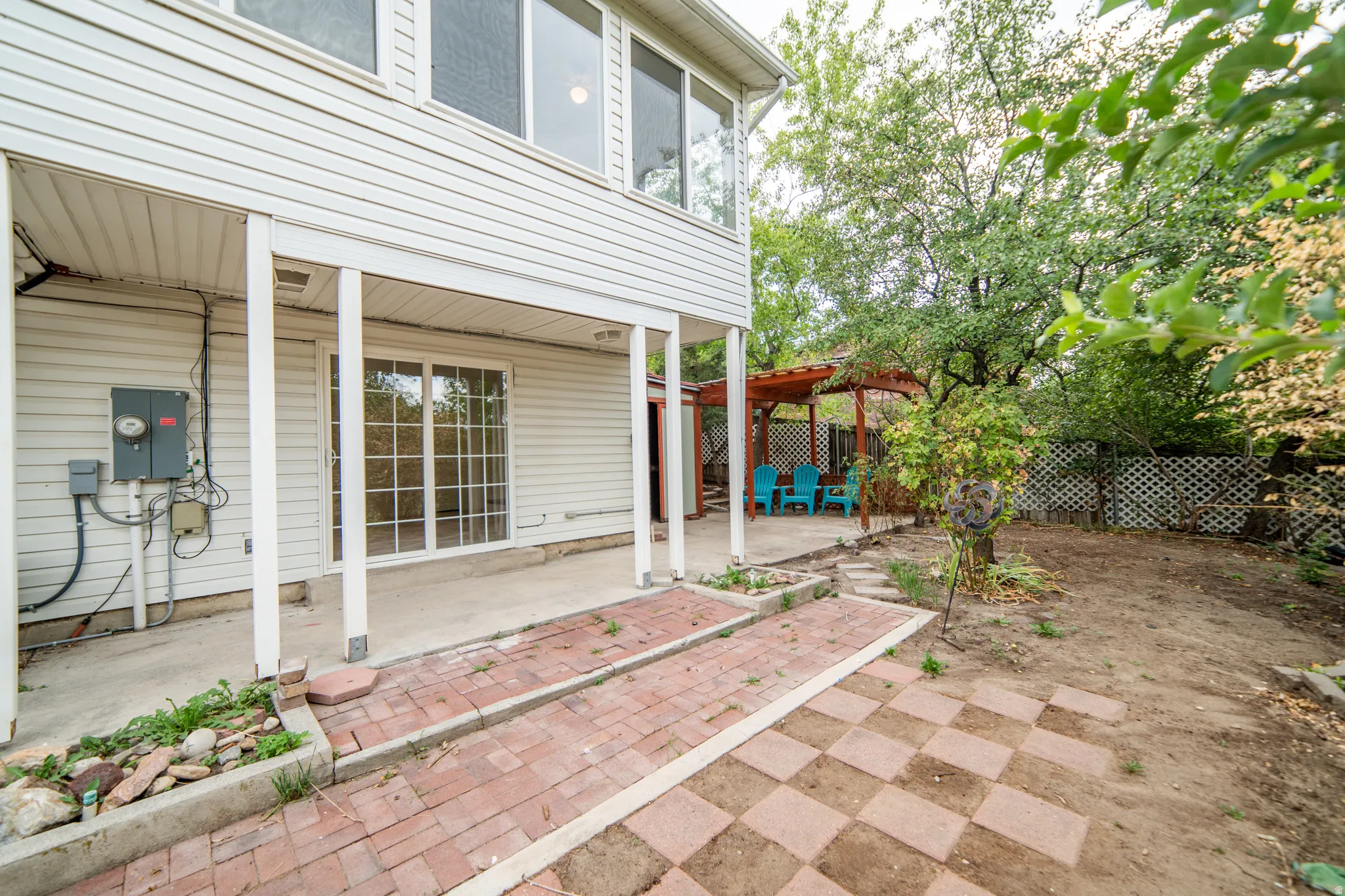 Covered patio with concrete flooring, sliding glass door, brick paver walkways, and a wood pergola