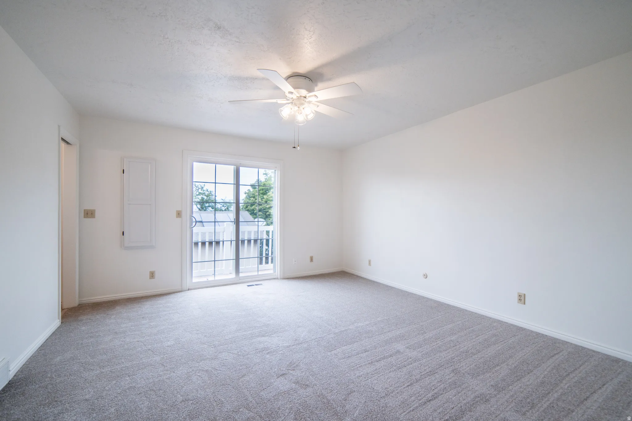 Neutral-toned carpeting, white walls, and a ceiling fan with integrated lighting