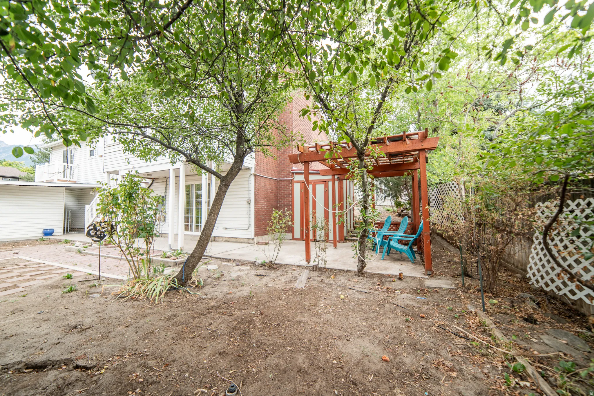 White siding exterior with a red brick chimney, a wood pergola, and a concrete patio