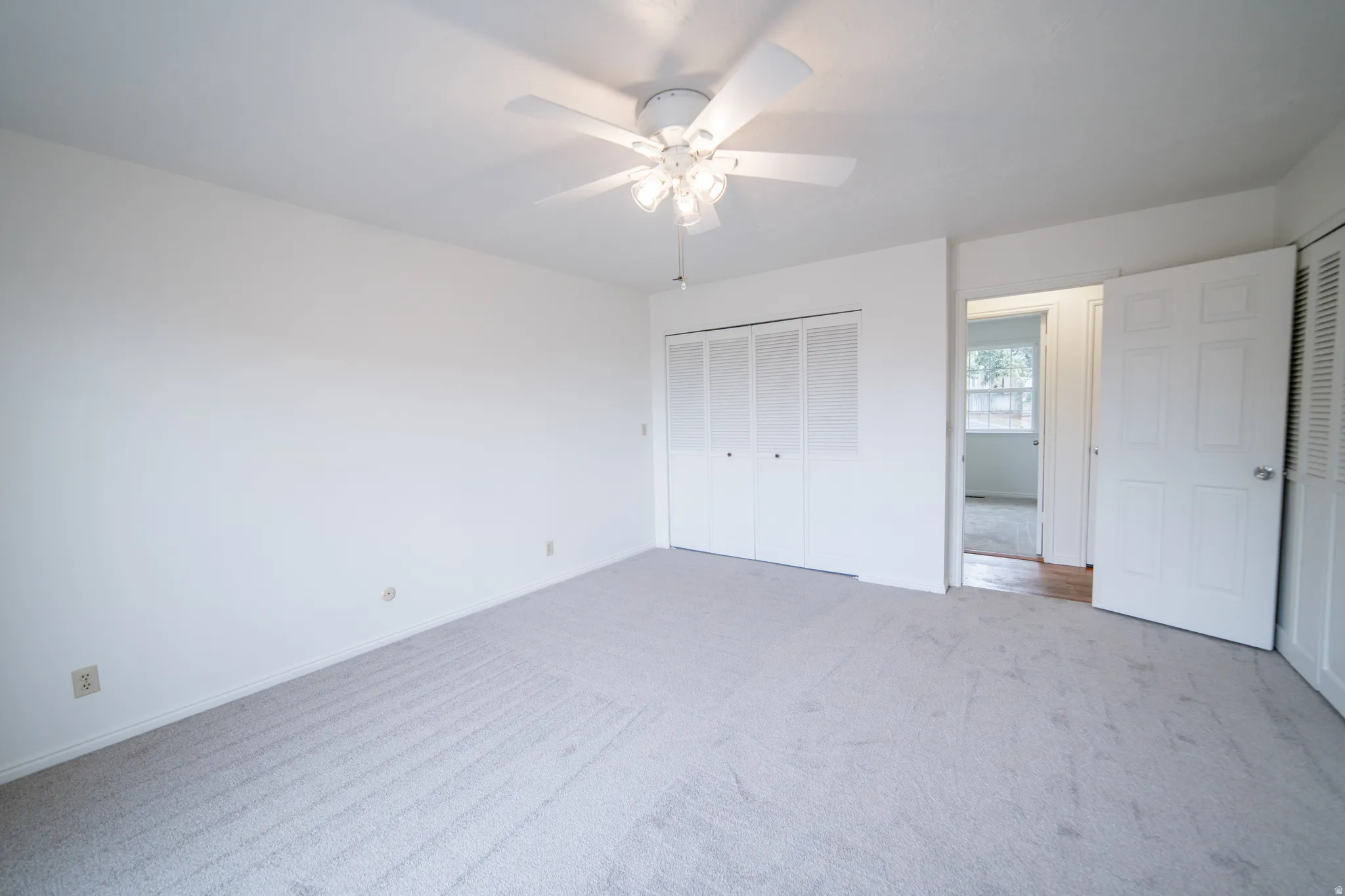 Neutral carpet flooring and white walls, with folding door closets.