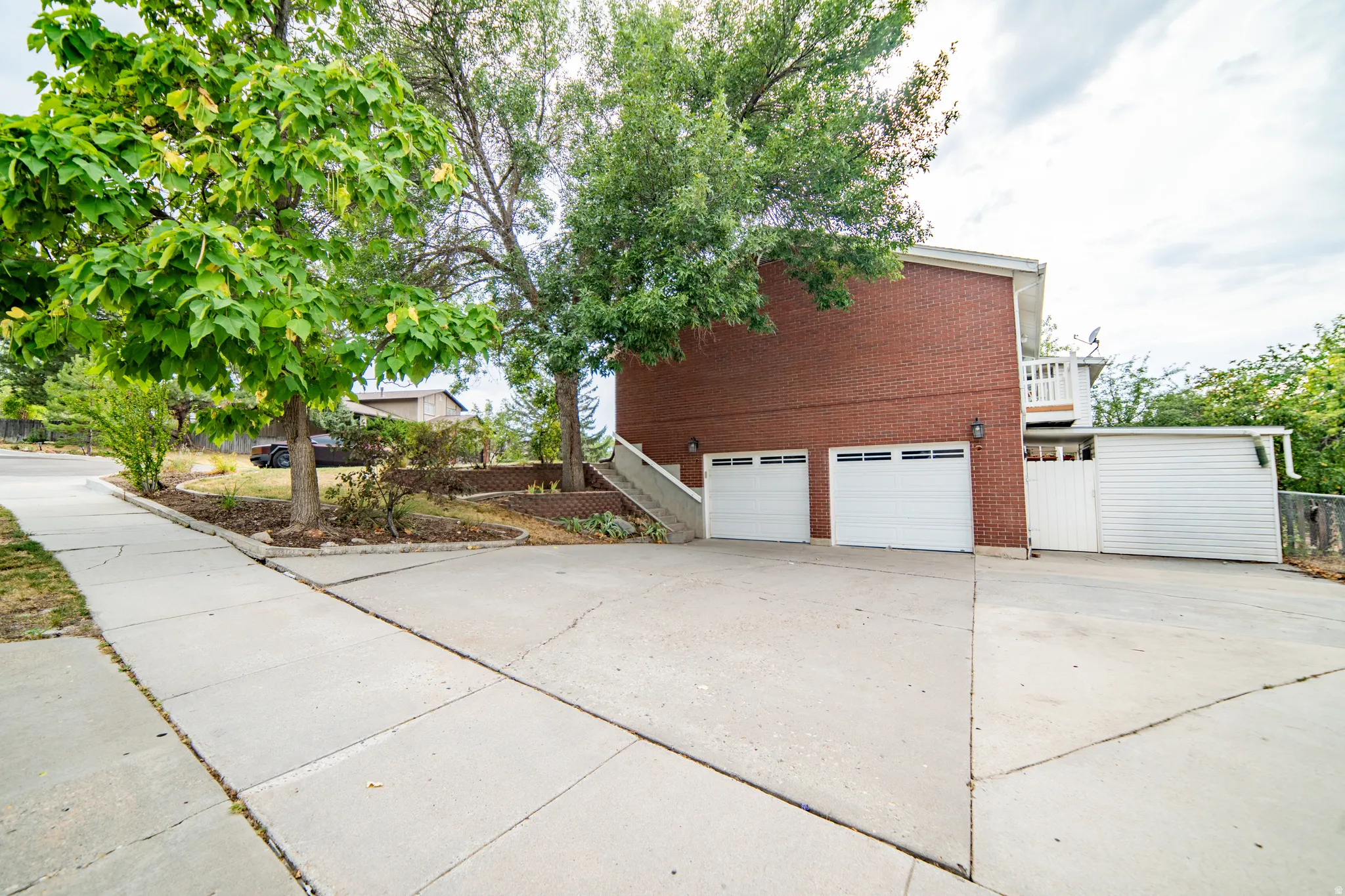 Brick exterior featuring a two-car garage with white doors, additional white siding, and a concrete driveway