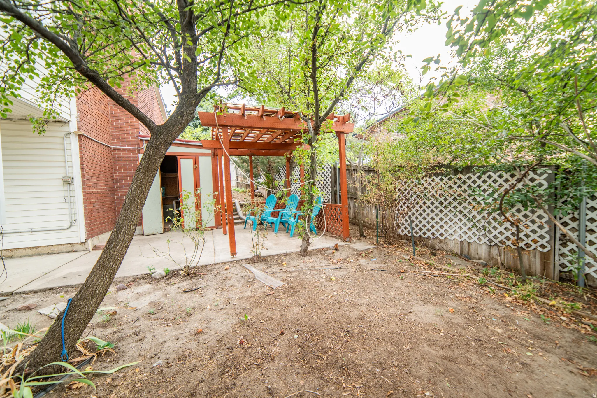 Concrete patio with an overhead wood pergola, and a privacy lattice fence