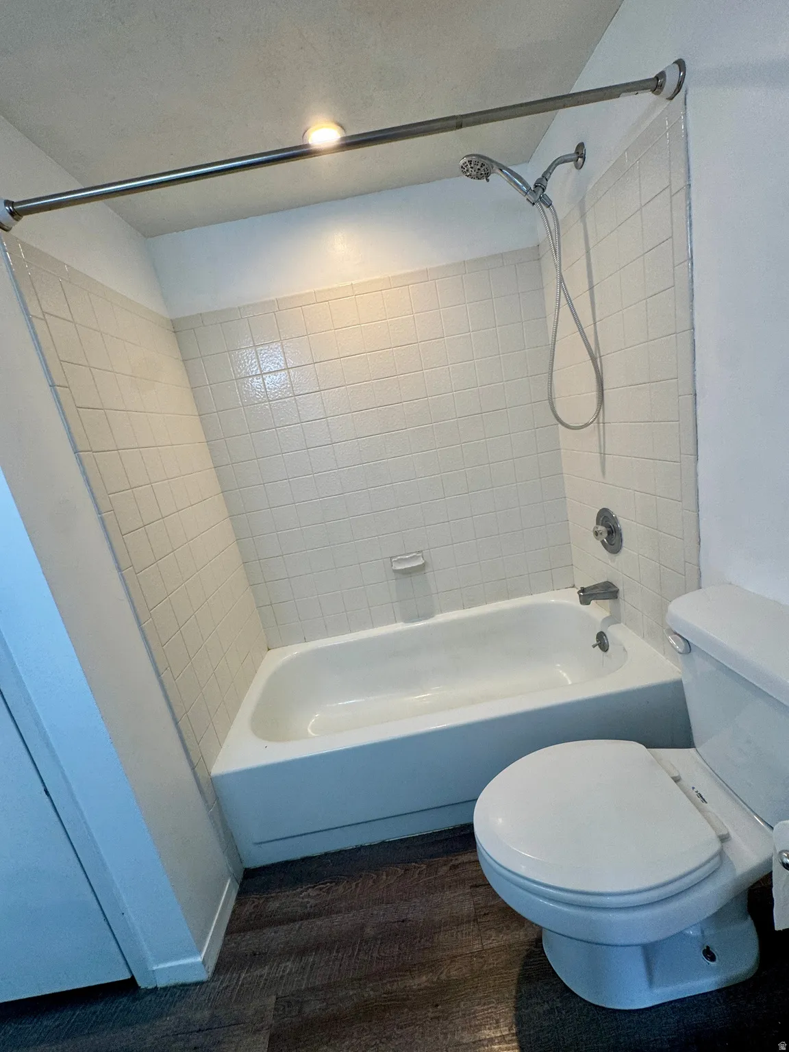 White ceramic tile surround, integrated bathtub, and a ceiling-mounted light fixture