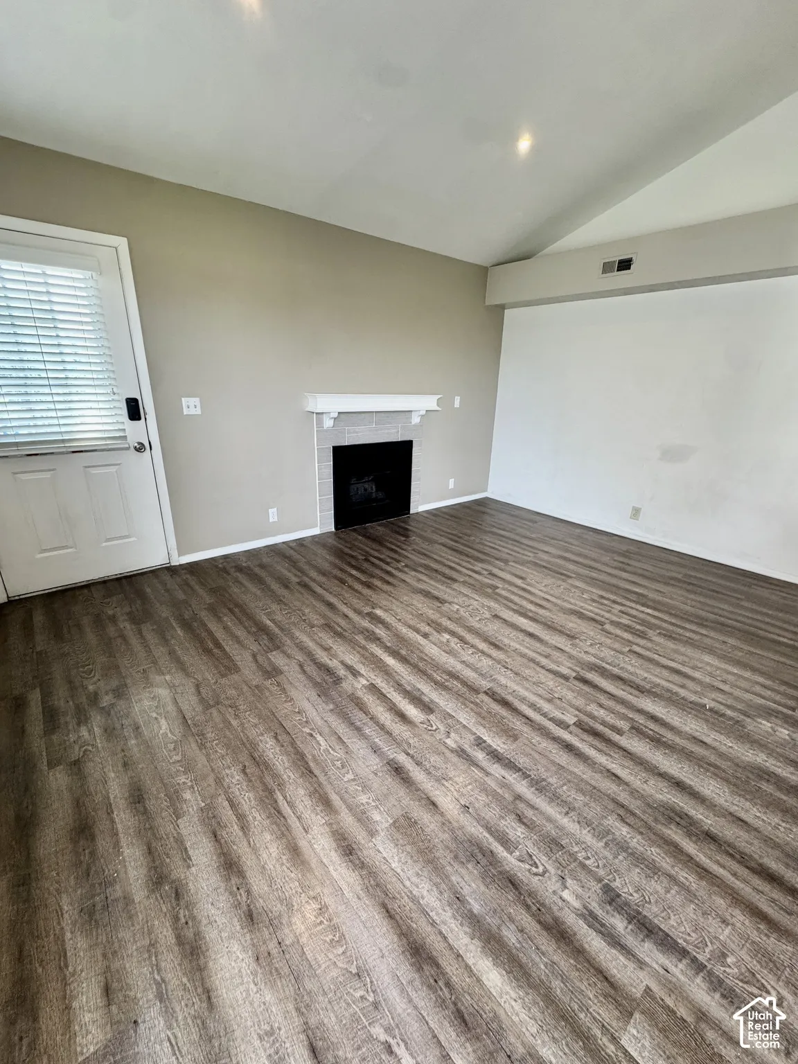 Wood-finish flooring, fireplace with tile surround and mantel, vaulted ceiling, and recessed lighting