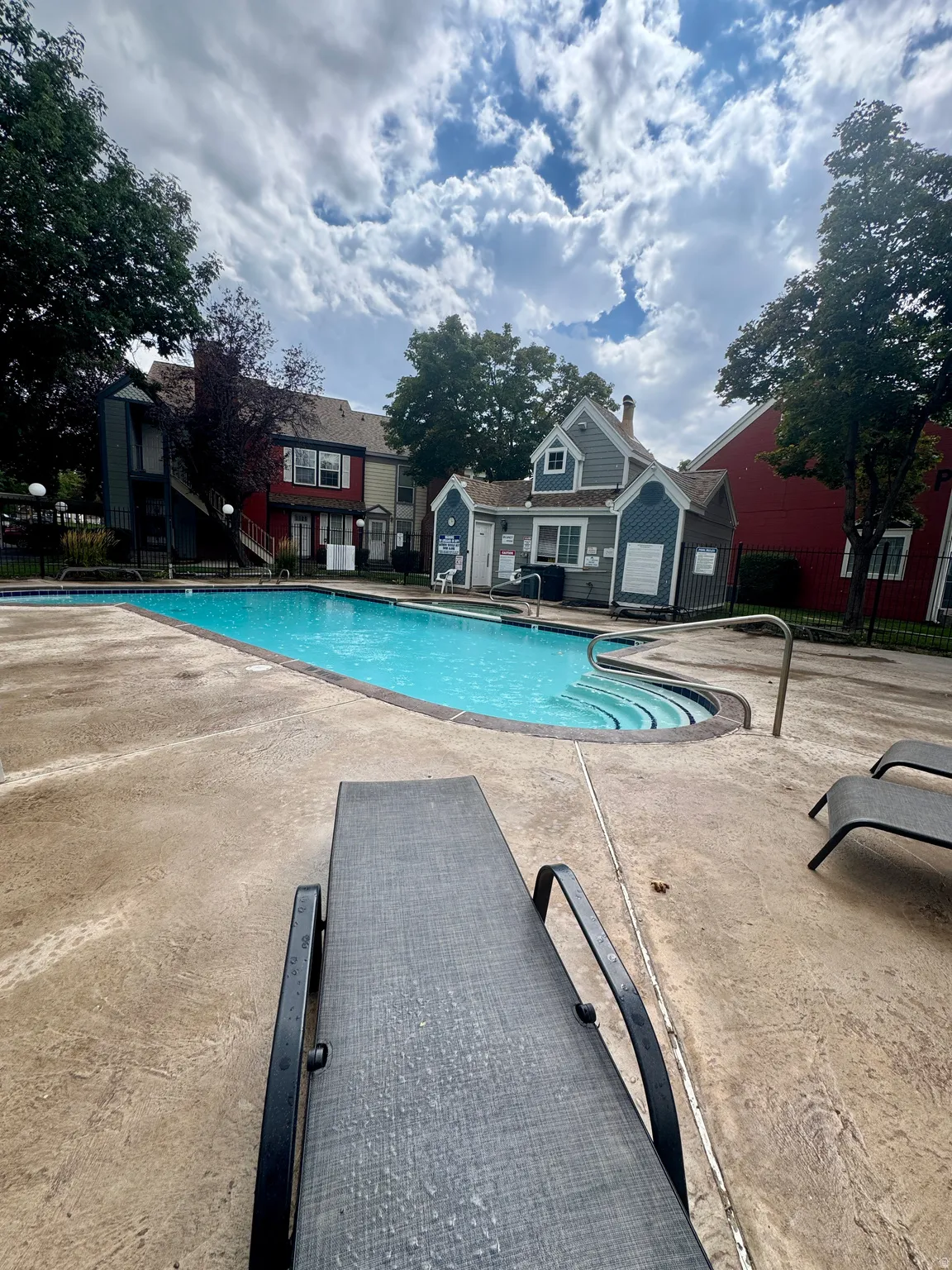 Swimming pool featuring steps, surrounding concrete decking, and a building with blue siding
