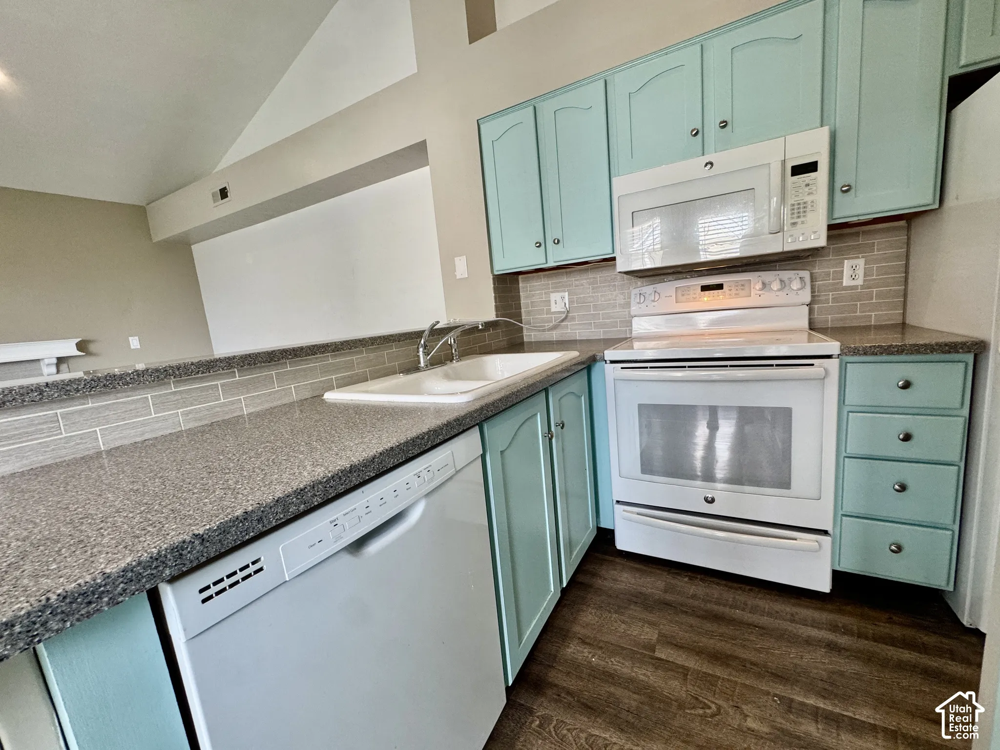 Kitchen featuring wood-finish flooring, light blue cabinetry, speckled countertops, and a subway tile backsplash