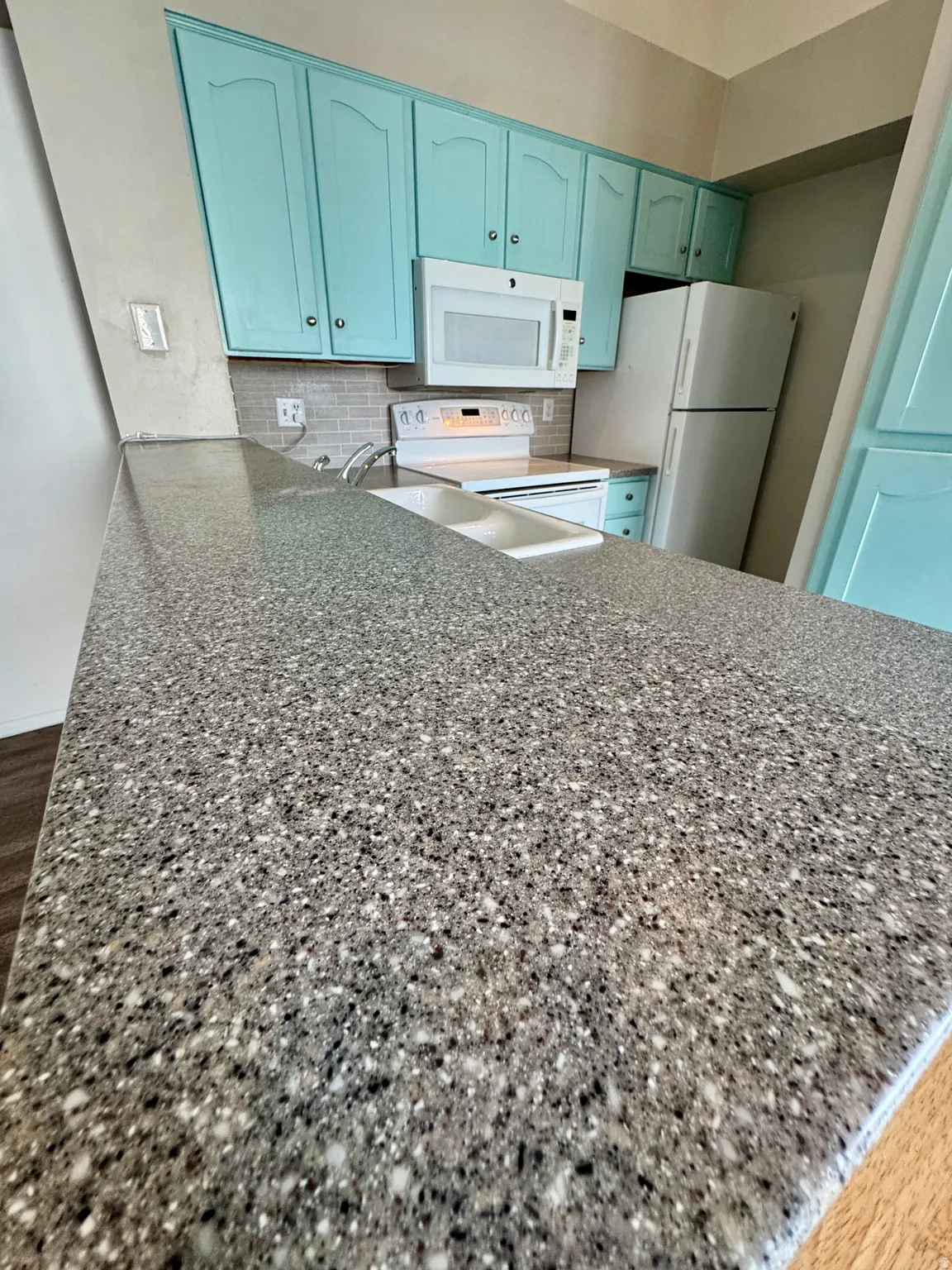 Granite-look countertop, integrated double basin sink, white built-in microwave, white electric range, and light blue cabinetry