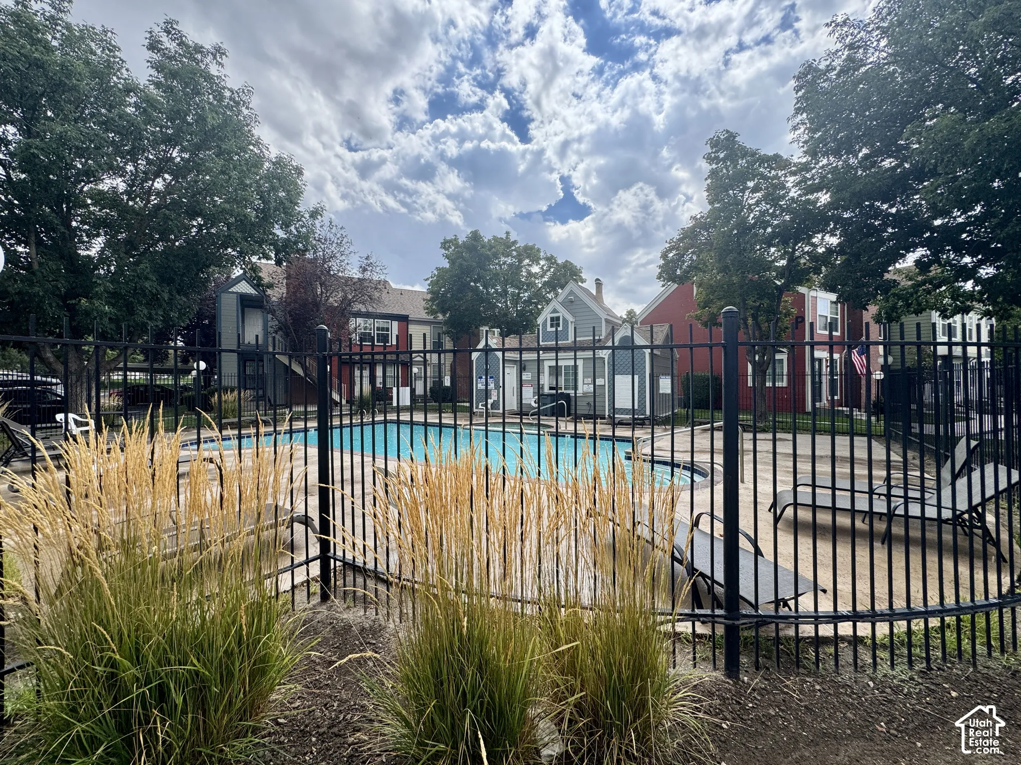Outdoor swimming pool with surrounding black metal fencing and concrete decking