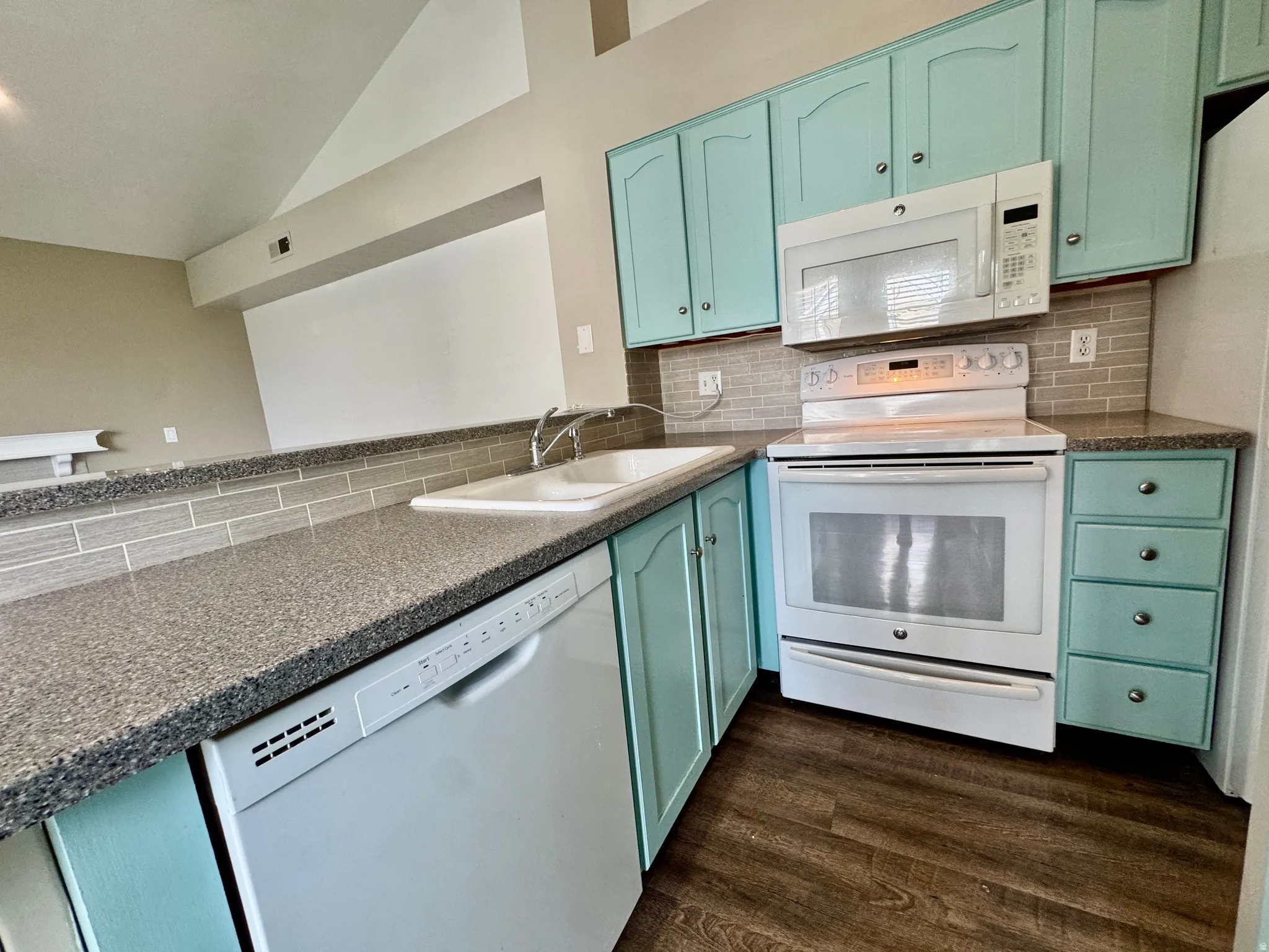 Kitchen featuring wood-finish flooring, light blue cabinetry, speckled countertops, and a subway tile backsplash