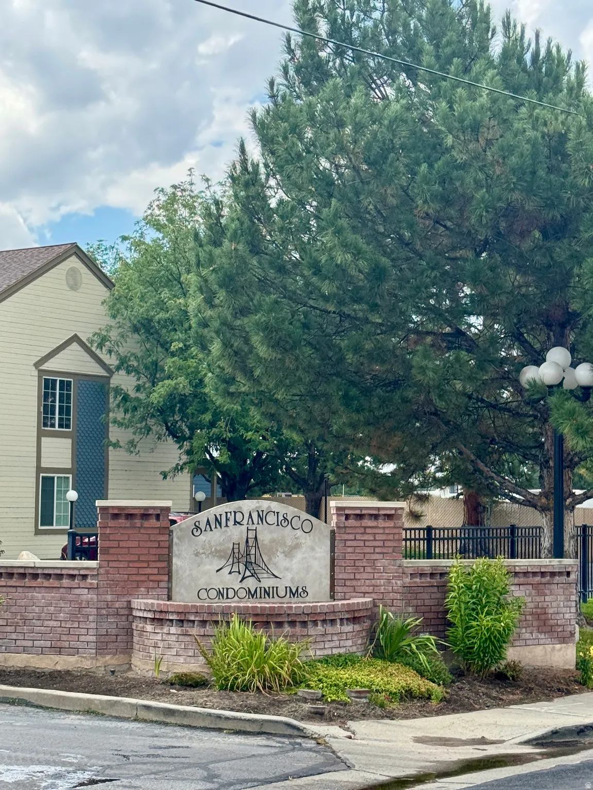 Brick and stucco monument sign, established landscaping, prominent evergreen trees