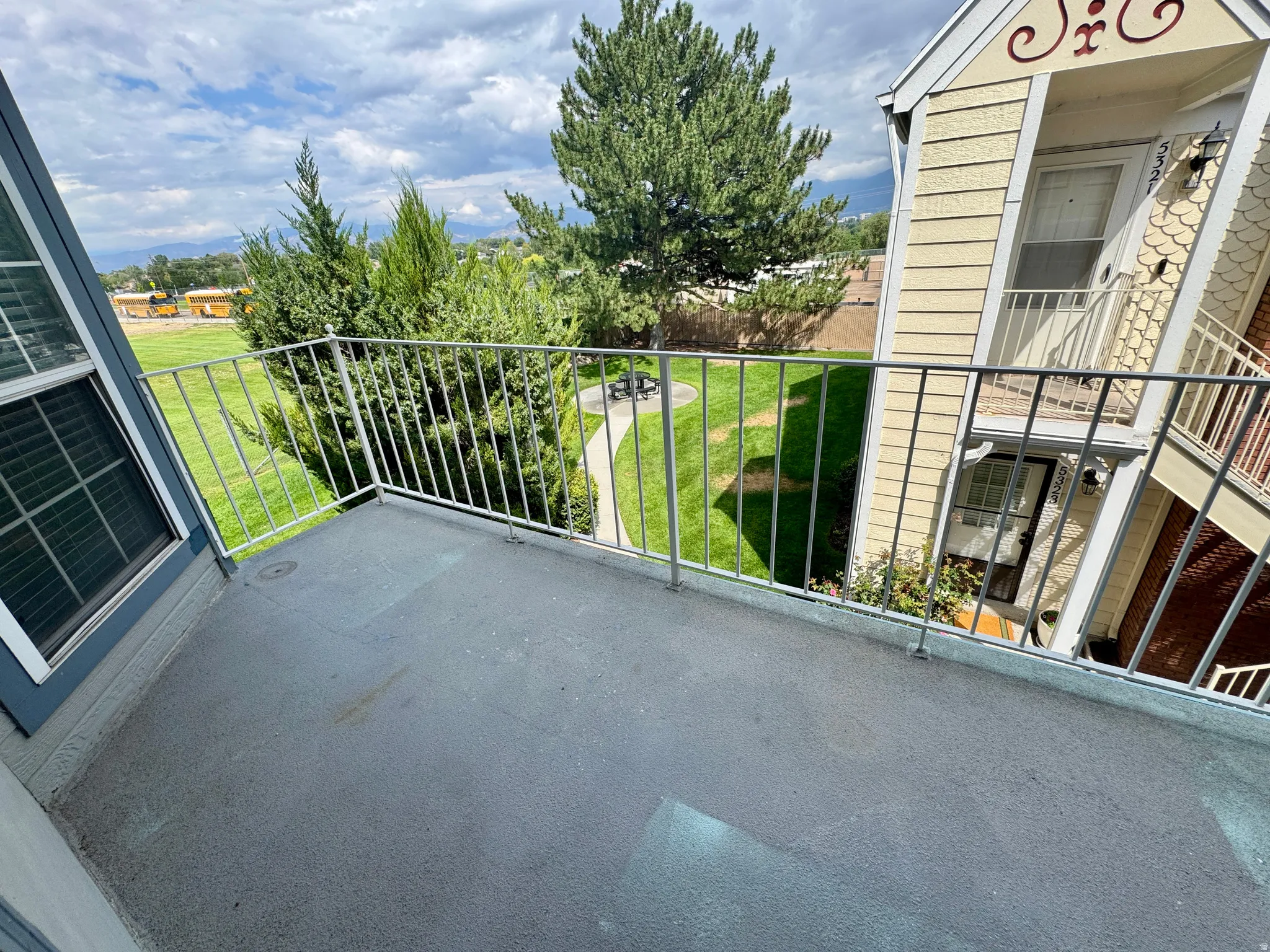 Private balcony with metal railing, offering expansive green grounds and distant landscape views