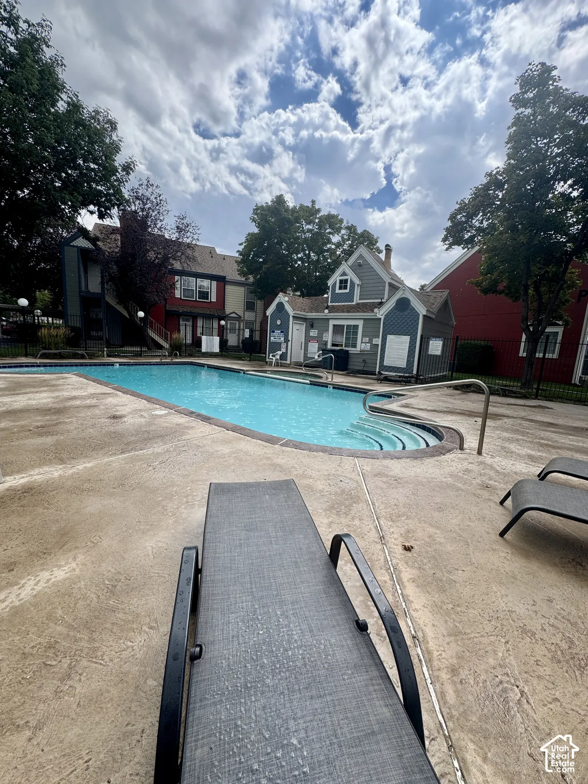 Swimming pool featuring steps, surrounding concrete decking, and a building with blue siding