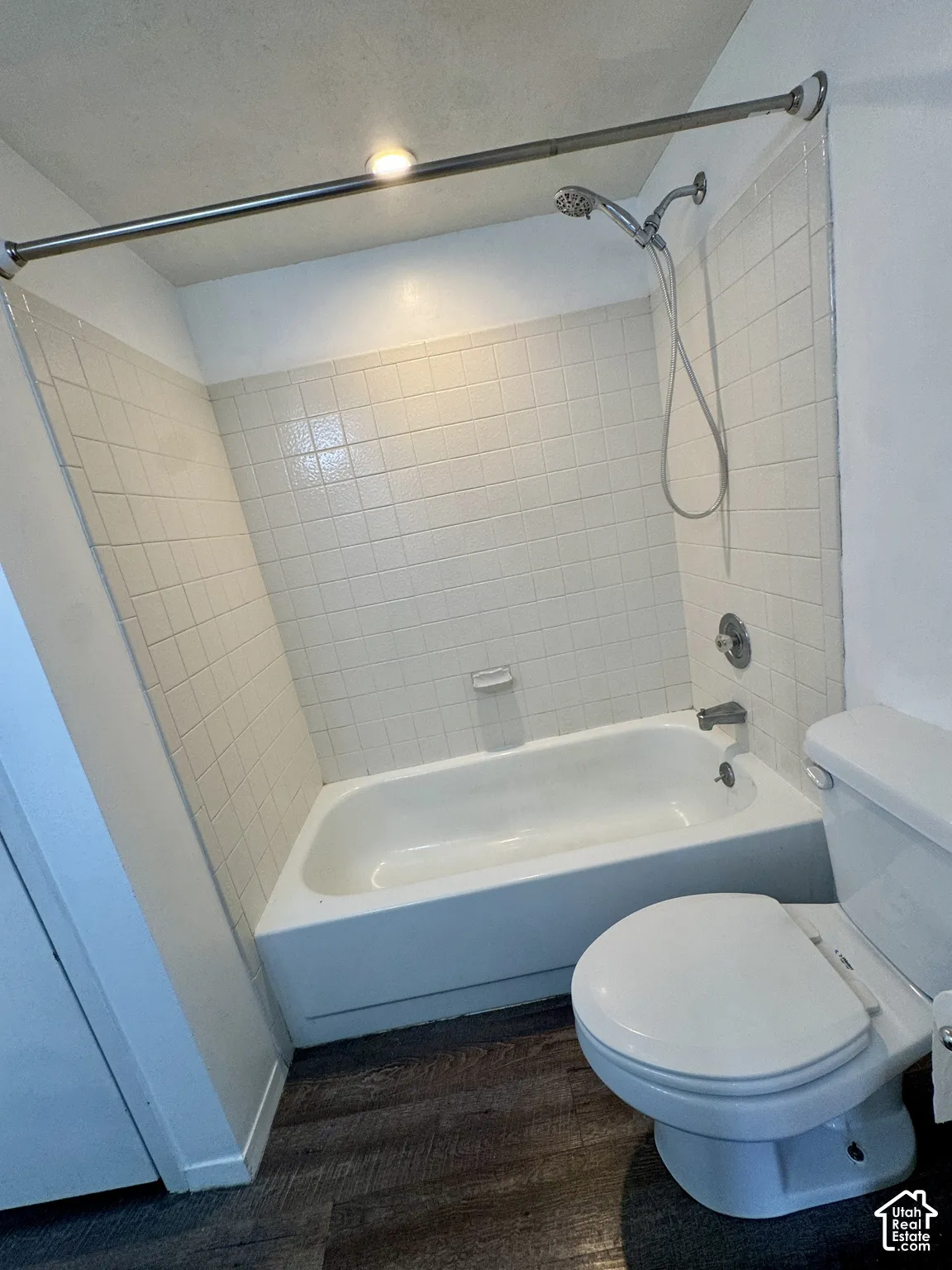White ceramic tile surround, integrated bathtub, and a ceiling-mounted light fixture