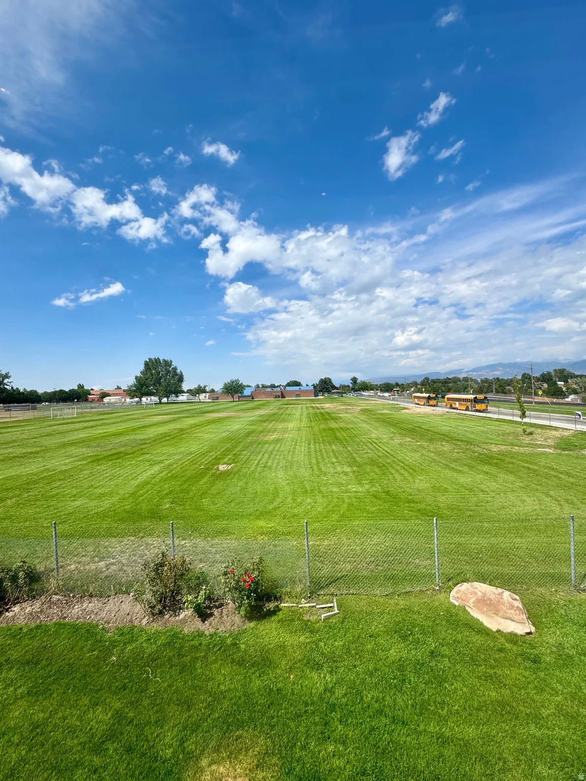 Manicured green lawn with a chain-link fence border