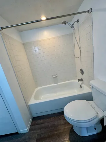 White ceramic tile surround, integrated bathtub, and a ceiling-mounted light fixture