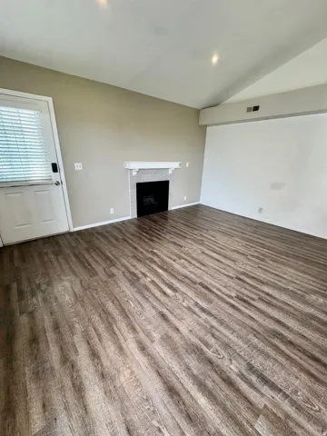 Wood-finish flooring, fireplace with tile surround and mantel, vaulted ceiling, and recessed lighting