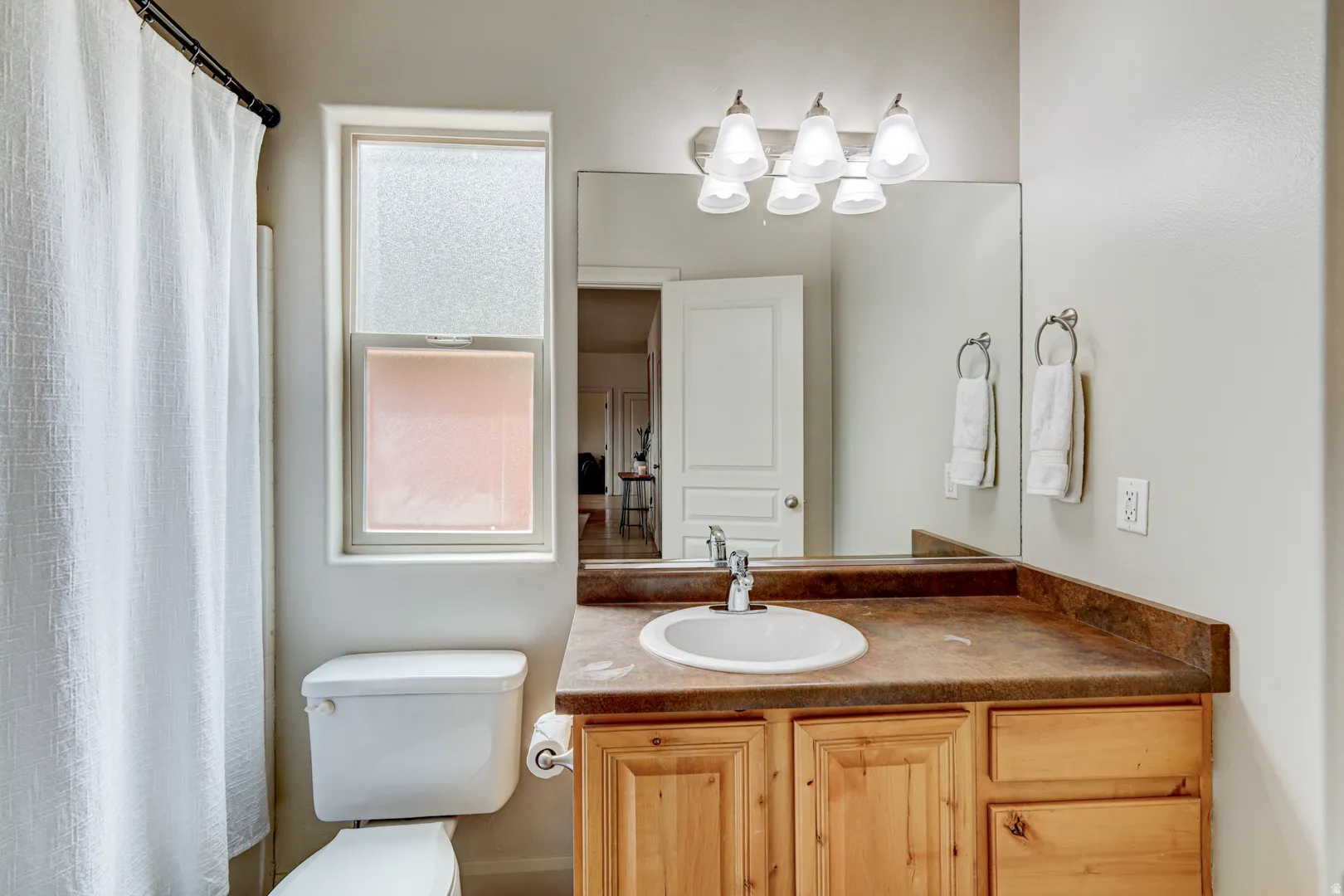 Bathroom featuring a vanity with a drop-in sink, wood-finish cabinetry, and a large wall mirror