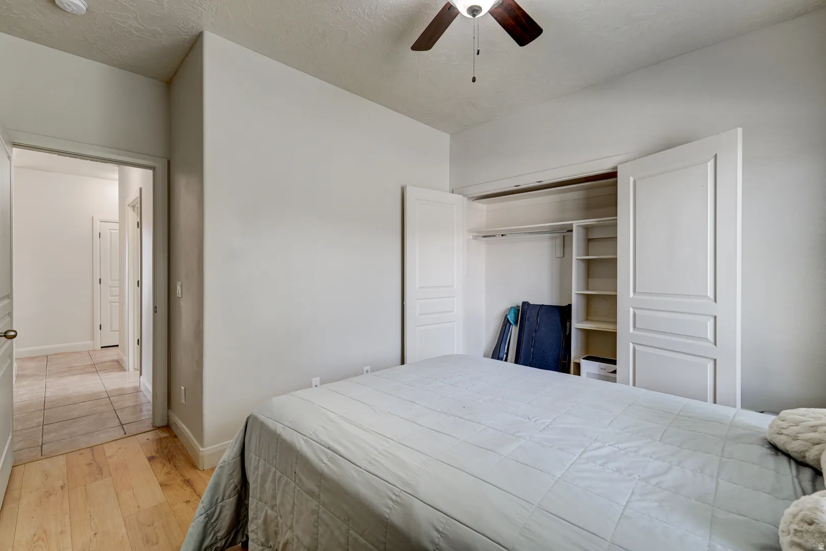 Hardwood-style flooring in bedroom, ceiling fan, and built-in closet shelving