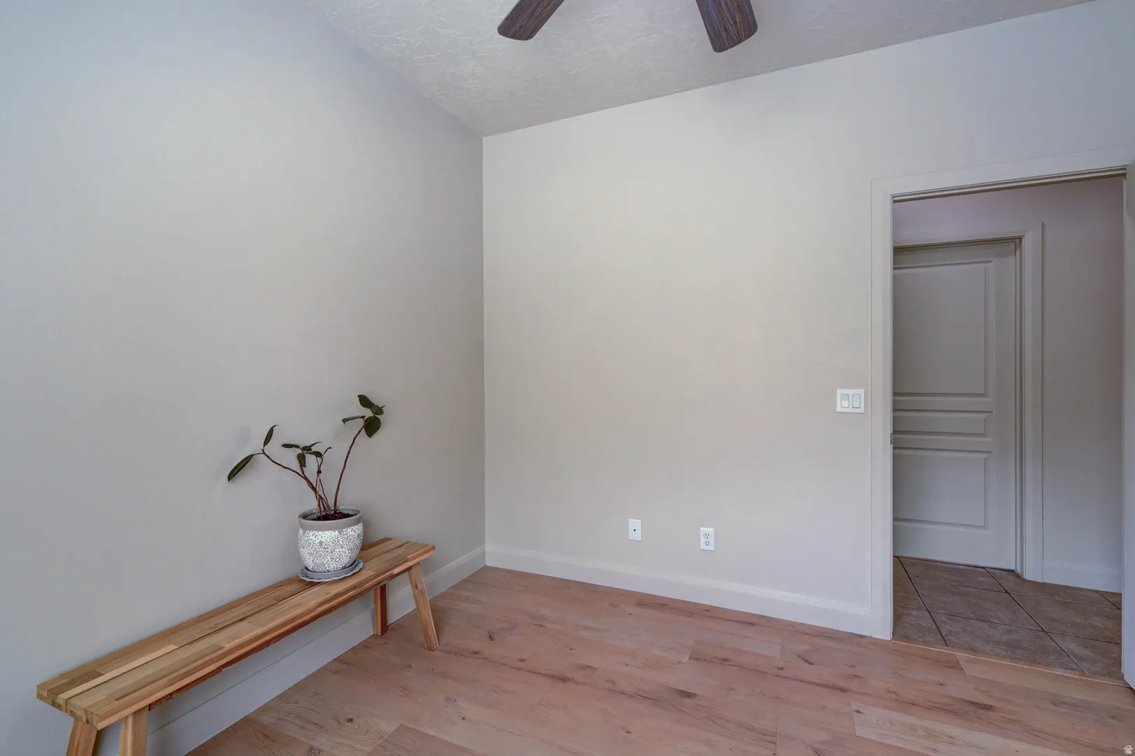 Wood-finish flooring, neutral wall tones, and overhead ceiling fan