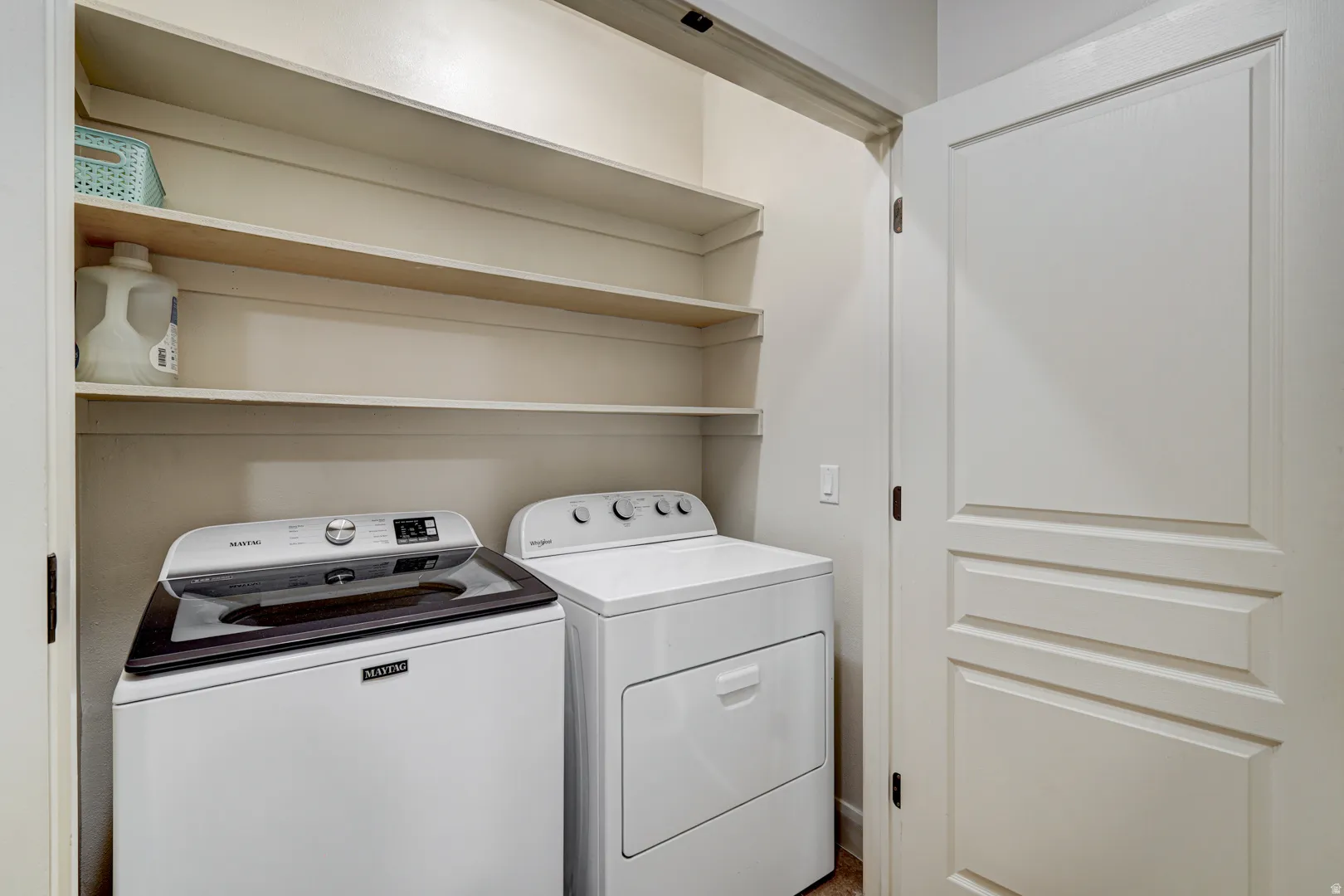 Built-in laundry closet with two appliances and overhead shelving