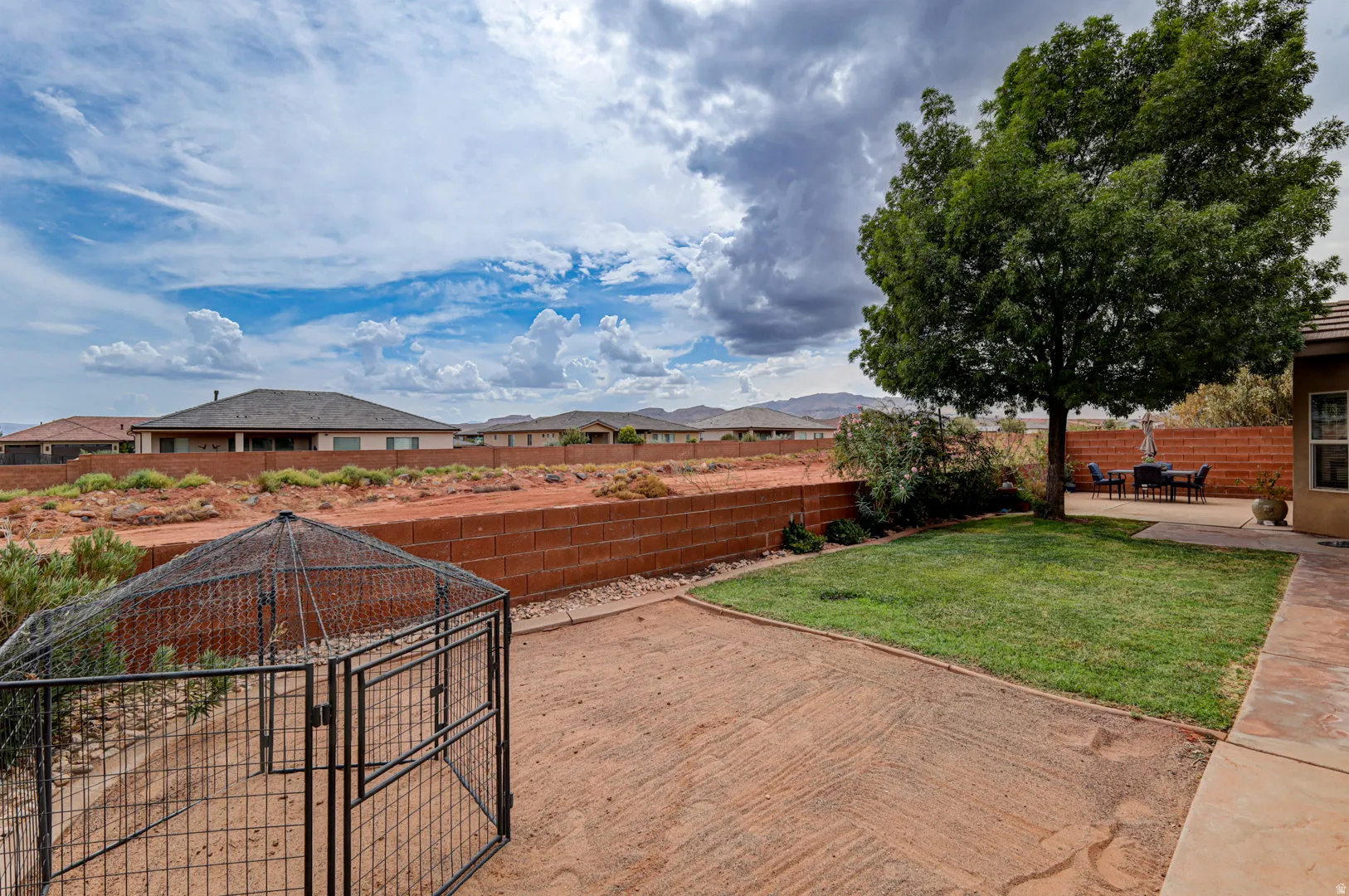 Expansive backyard featuring a mature tree, concrete patio, and a manicured lawn