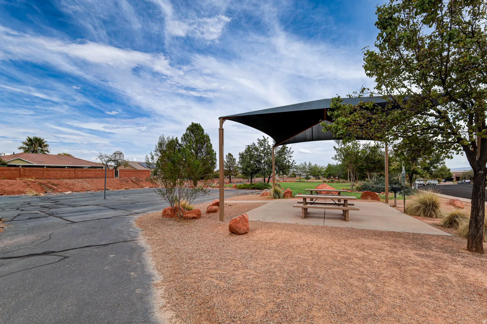 Shaded outdoor seating area with a picnic table, concrete pad, and gravel landscaping