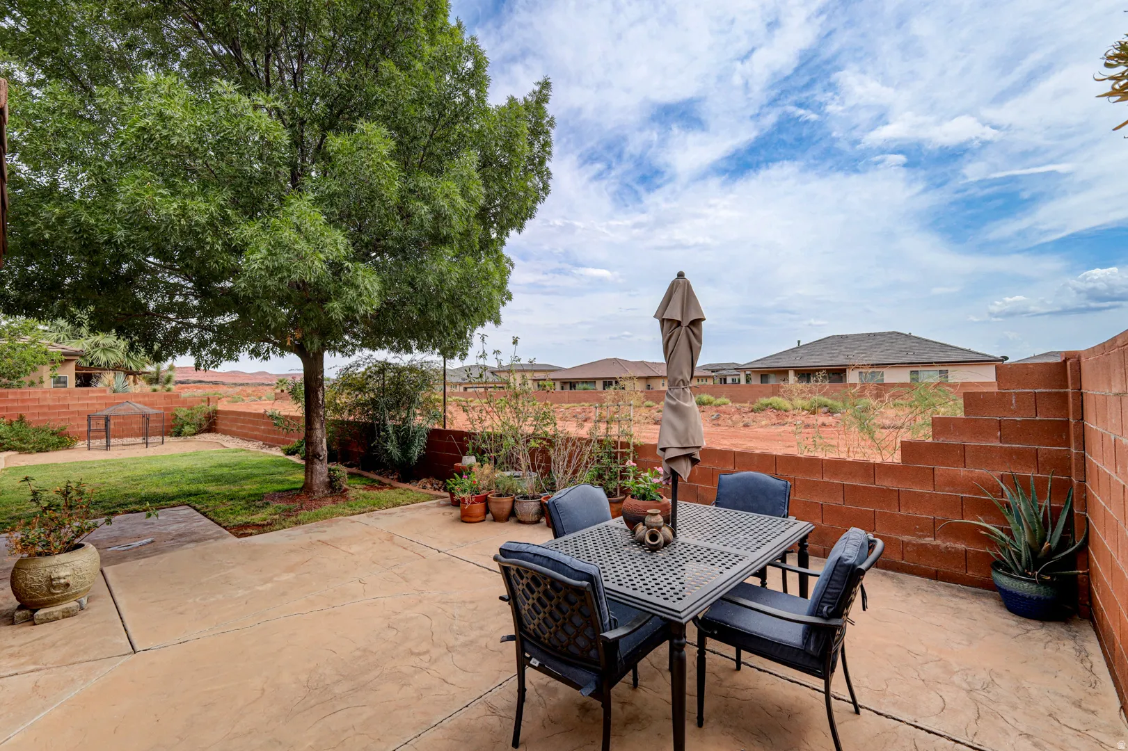 Stamped concrete patio with a privacy wall, mature tree, and green lawn