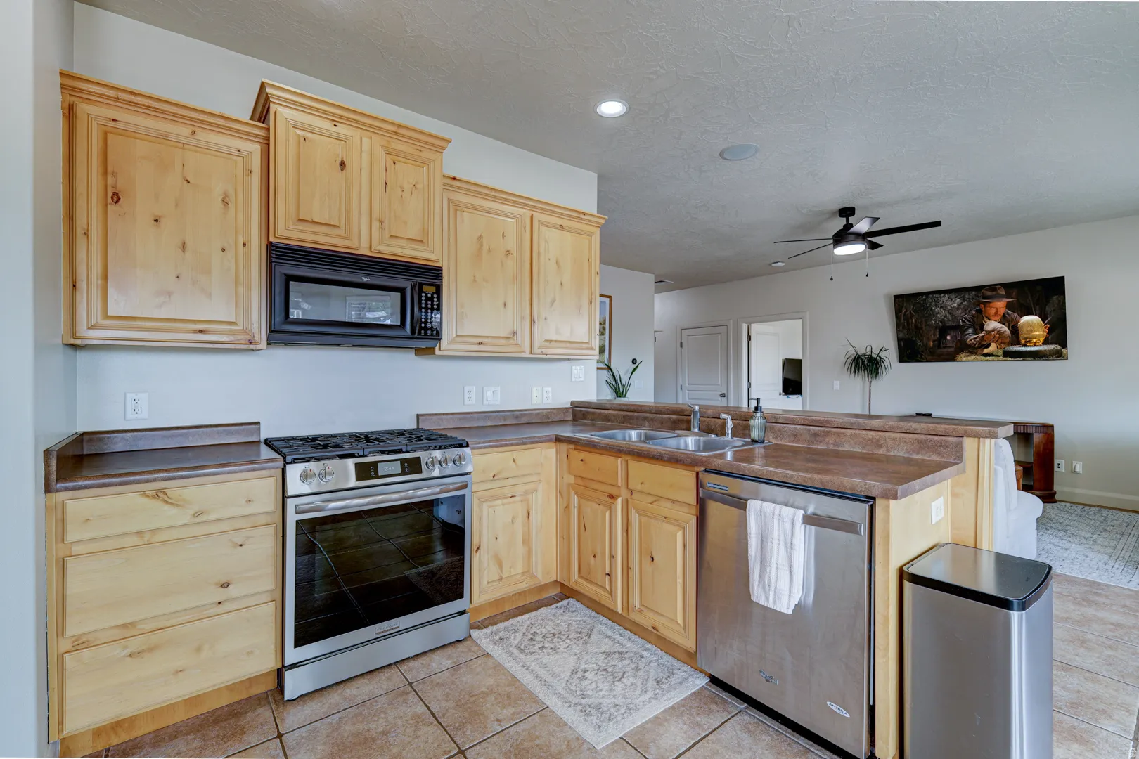 Kitchen featuring natural wood cabinetry, stainless steel range, stainless steel dishwasher, and a double basin sink