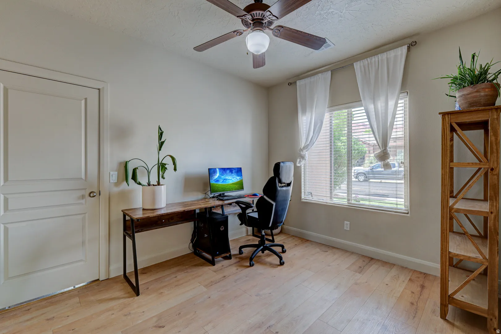 Wood-finish flooring, ceiling fan with integrated lighting, and a window with horizontal blinds