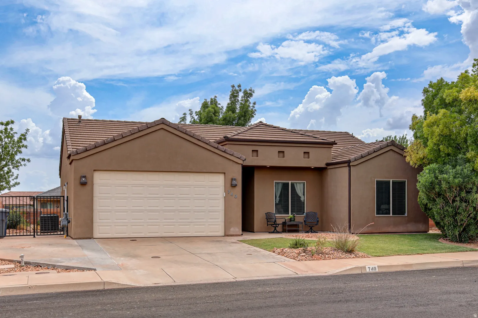 Stucco exterior with a tiled roof, featuring an attached garage with a paved driveway