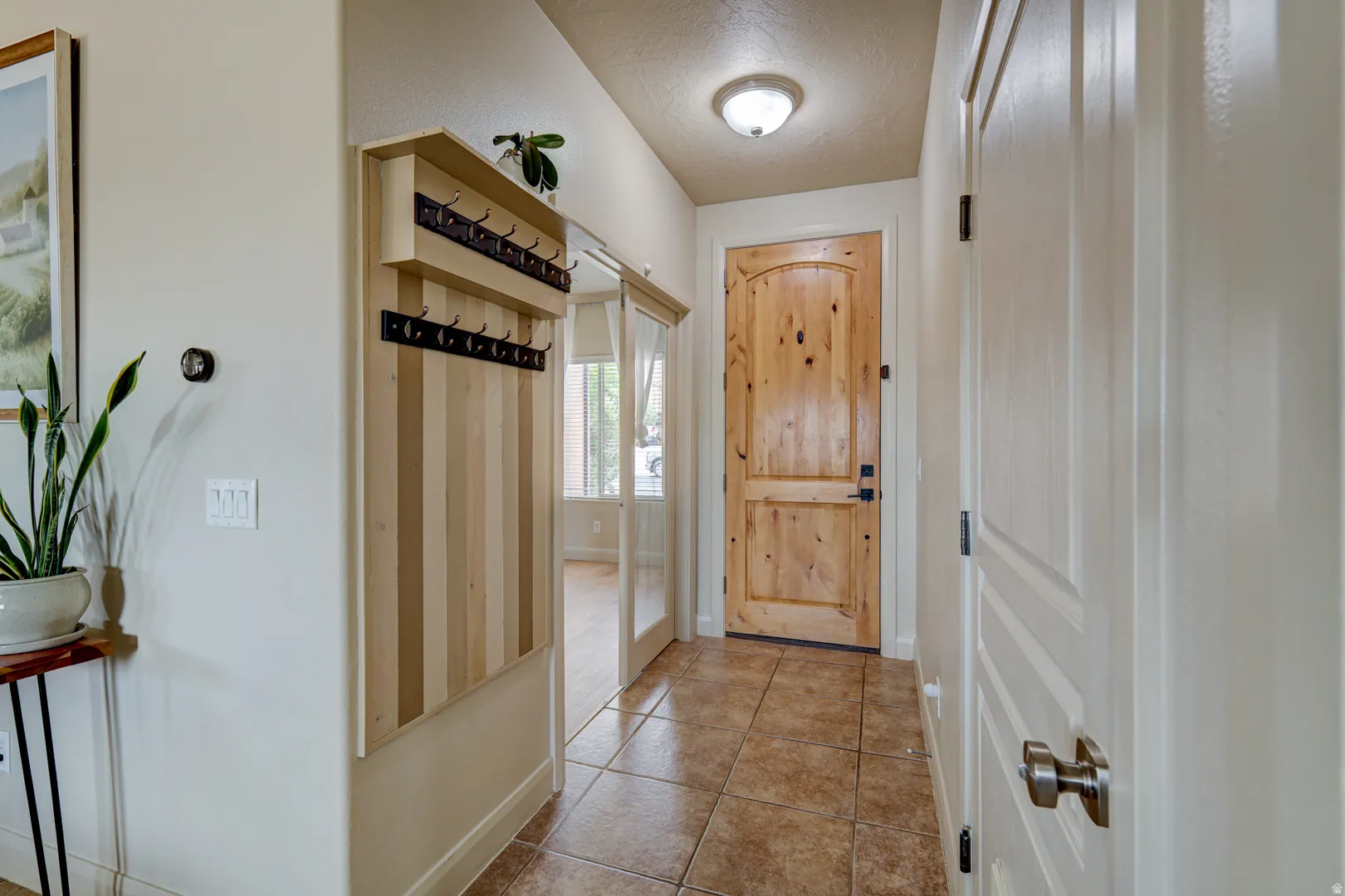 Entryway featuring tiled flooring, a solid wood entry door, and a built-in coat rack with shelving