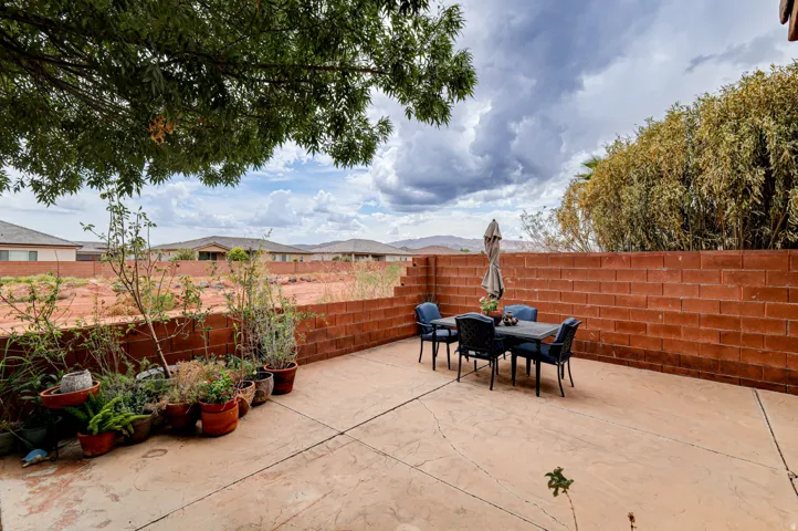 Concrete patio with a red brick privacy wall and mature trees