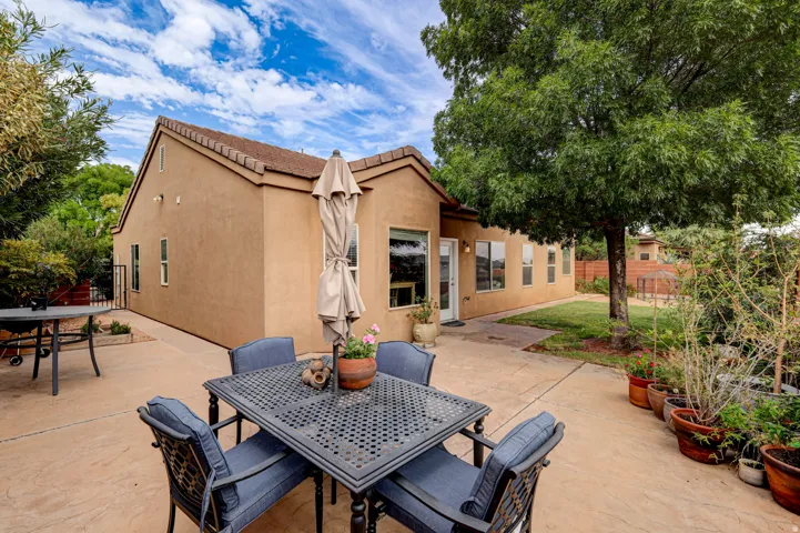 Exterior stucco finish with a tile roof, featuring multiple windows, a rear entry door, and an expansive stamped concrete patio