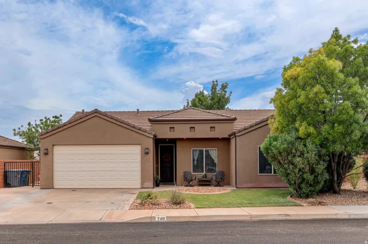 Stucco exterior with a tiled roof, integrated garage, and a landscaped front yard featuring mature trees and shrubs