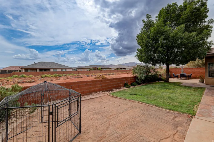Expansive backyard featuring a mature tree, concrete patio, and a manicured lawn