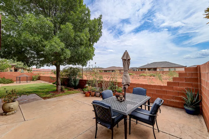 Stamped concrete patio with a privacy wall, mature tree, and green lawn