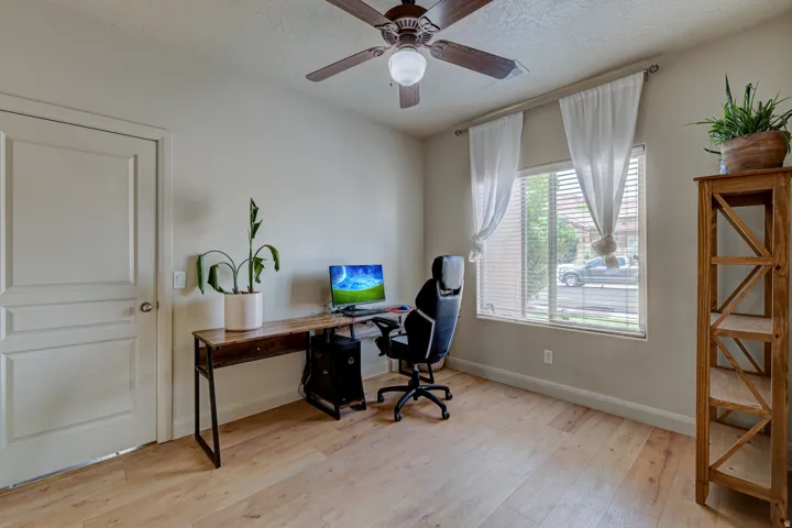 Wood-finish flooring, ceiling fan with integrated lighting, and a window with horizontal blinds
