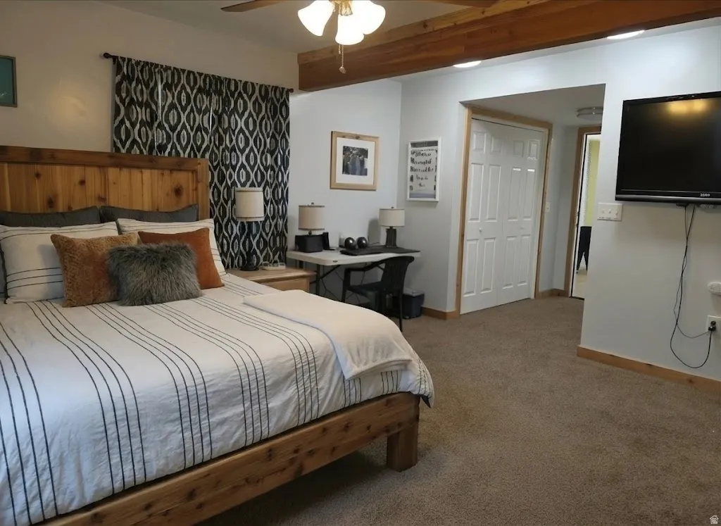 Carpeted flooring, wood-finish ceiling beams, ceiling fan, bi-fold closet doors, and wood-finish trim throughout