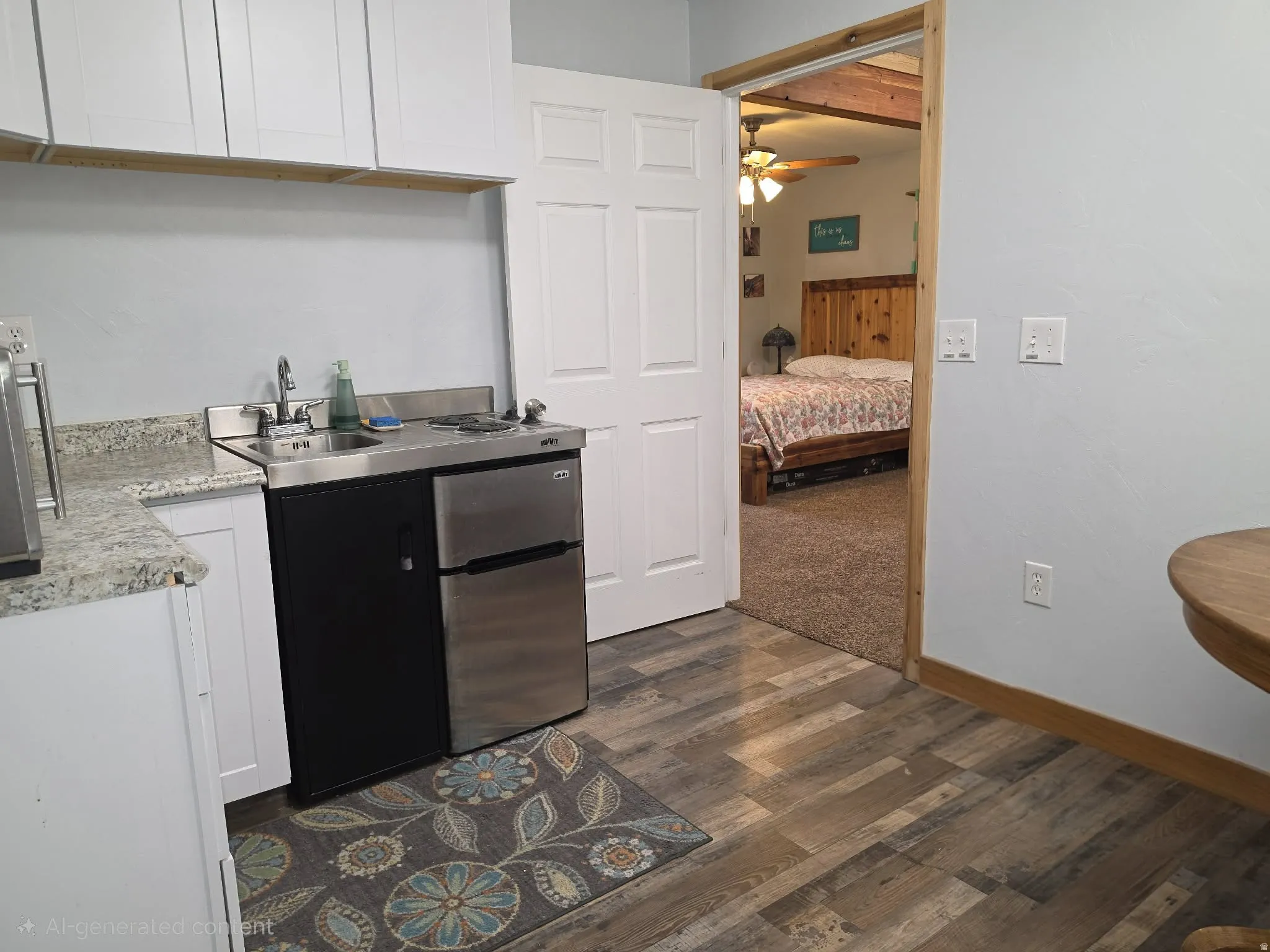 Efficient kitchenette featuring stainless steel appliances, white cabinetry with wood-finish accents, granite-look countertops, and wood-finish flooring throughout