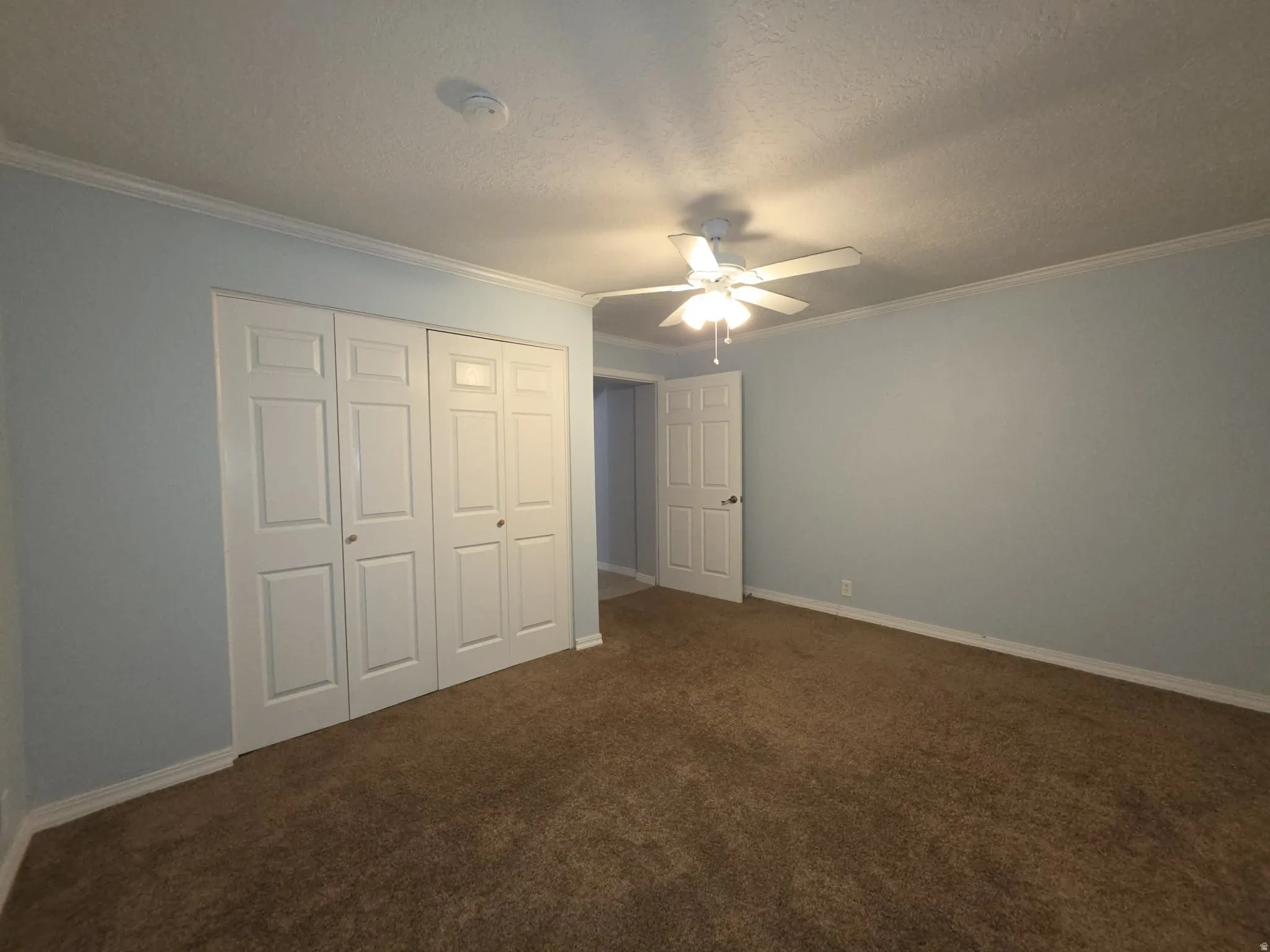 Wall-to-wall carpeting, ceiling fan with integrated lighting, bi-fold closet doors, and crown molding
