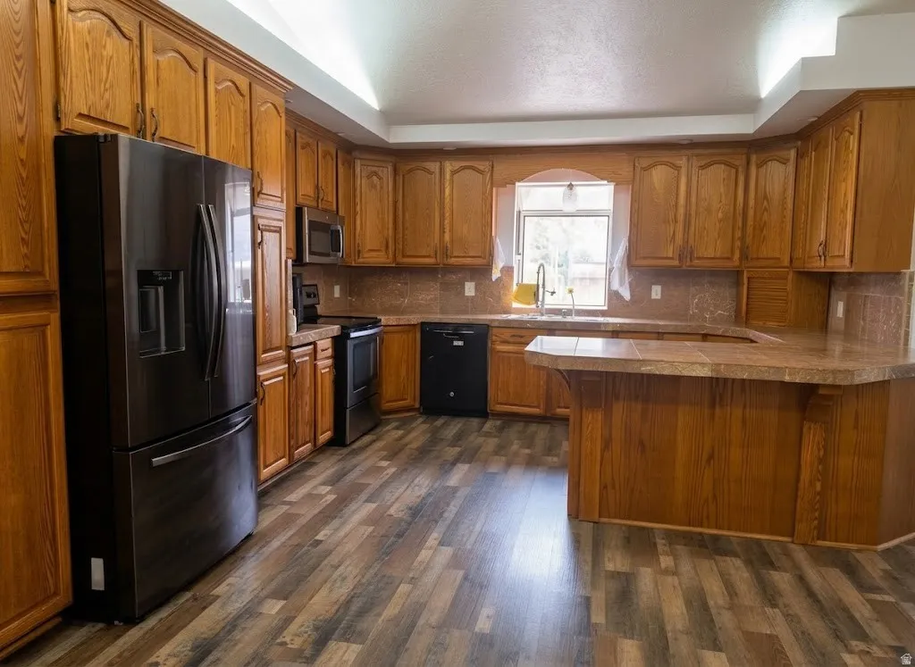 Expansive kitchen featuring wood-finish cabinetry, tile countertops, and wood-finish flooring