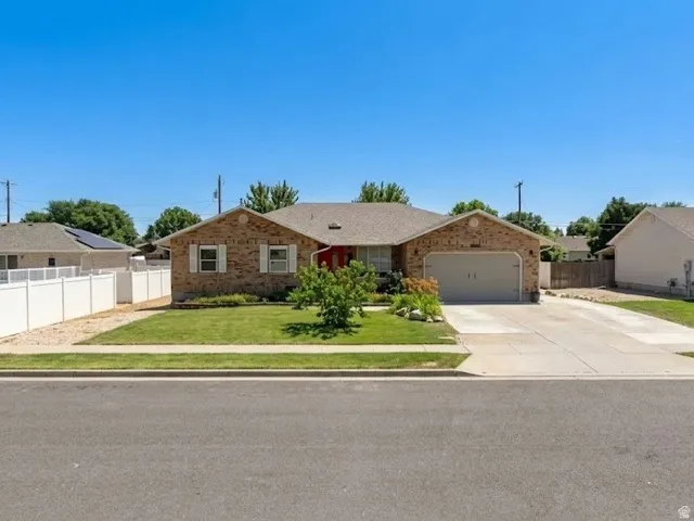 Brick exterior with attached garage, concrete driveway, and manicured front lawn