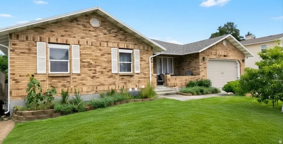 Brick exterior, attached garage, covered front porch, white window shutters, and a manicured lawn