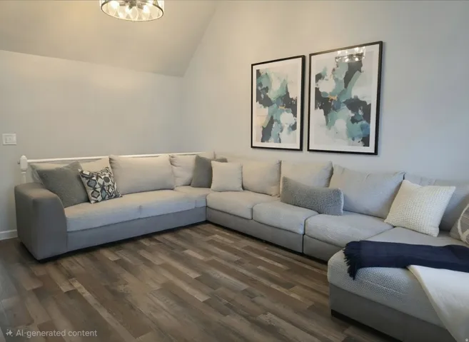 Vaulted ceiling with a contemporary flush-mount light fixture, wood-finish flooring, and light gray wall paint
