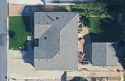 Main dwelling with multi-pitched roof, detached auxiliary building, concrete driveway, and landscaped green spaces