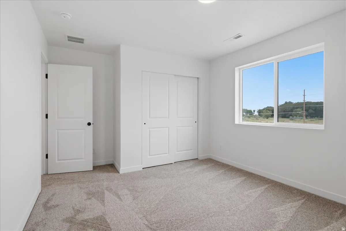 Carpeted room with a sliding closet door, white trim, recessed lighting, and a large window