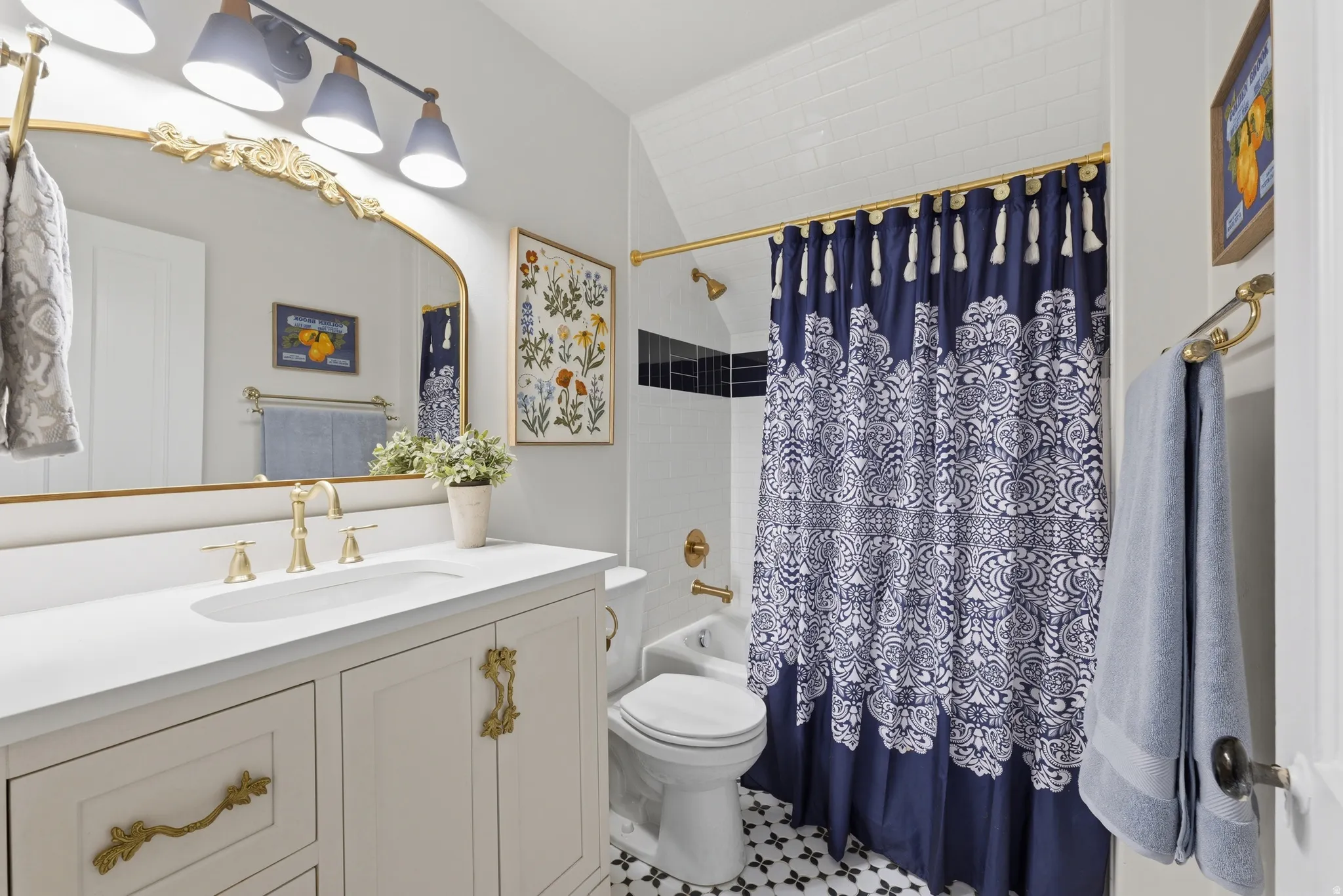 White vanity with ornate gold hardware, white countertop, undermount sink, and brass-finish faucet