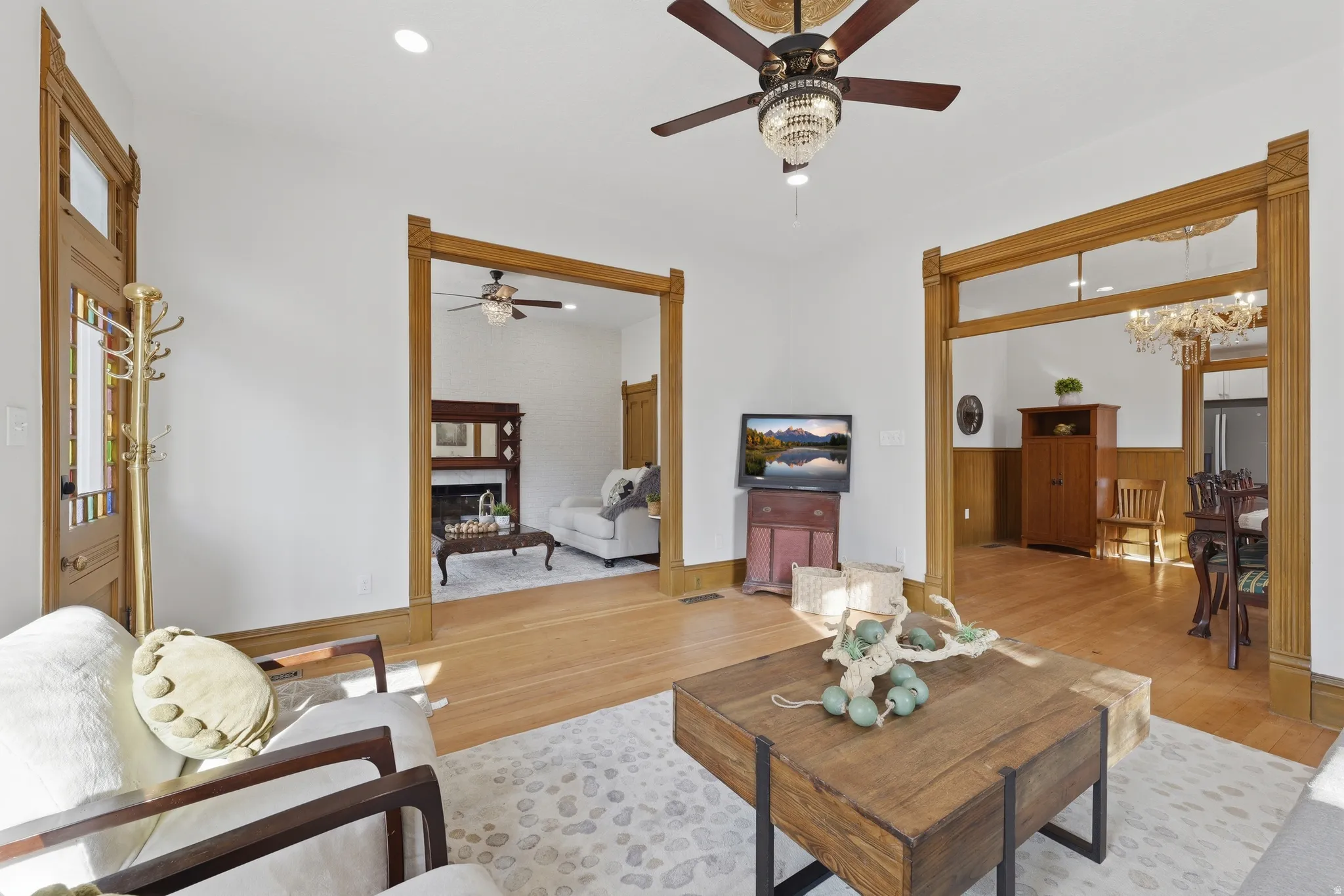Hardwood flooring, ornate ceiling fan with chandelier, white walls, and wood trim throughout
